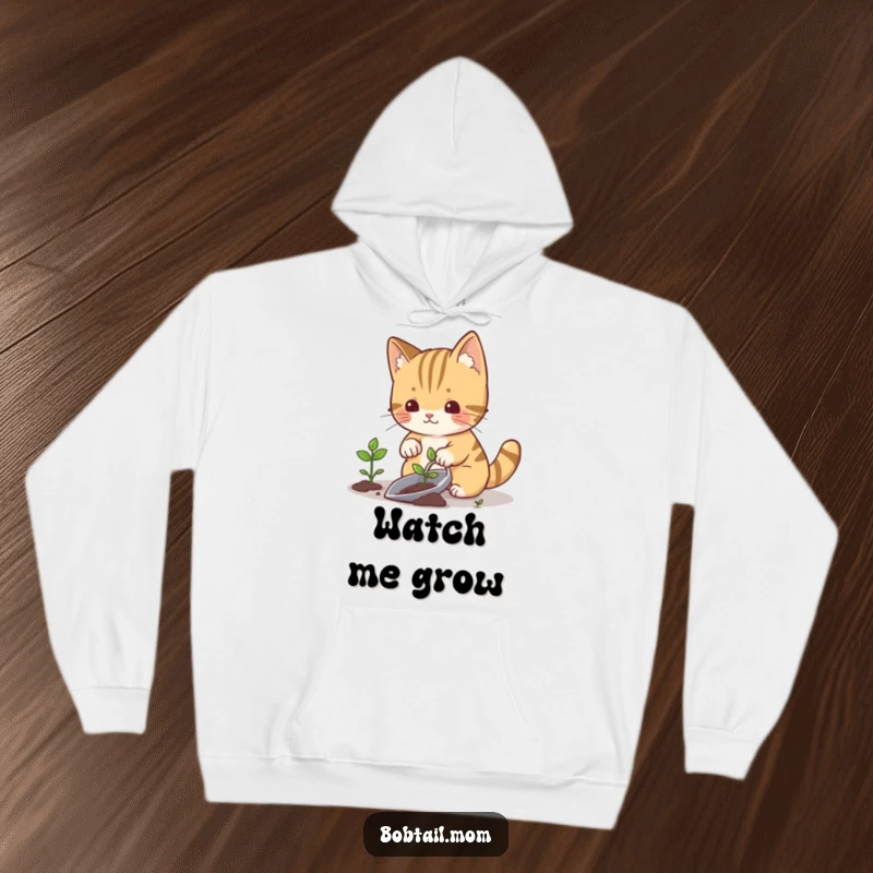 Funny bobtail cat holding a gardening trowel, planting a small sprout, looking content, perfect for a cozy hoodie.